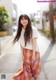 A woman in a white shirt and orange plaid skirt posing for a picture.